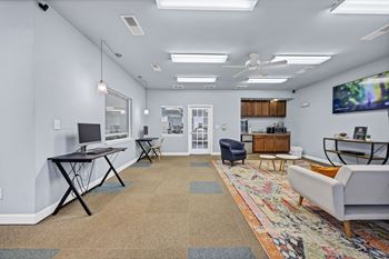 A living room with a white couch, a black table, and a rug with a colorful design.